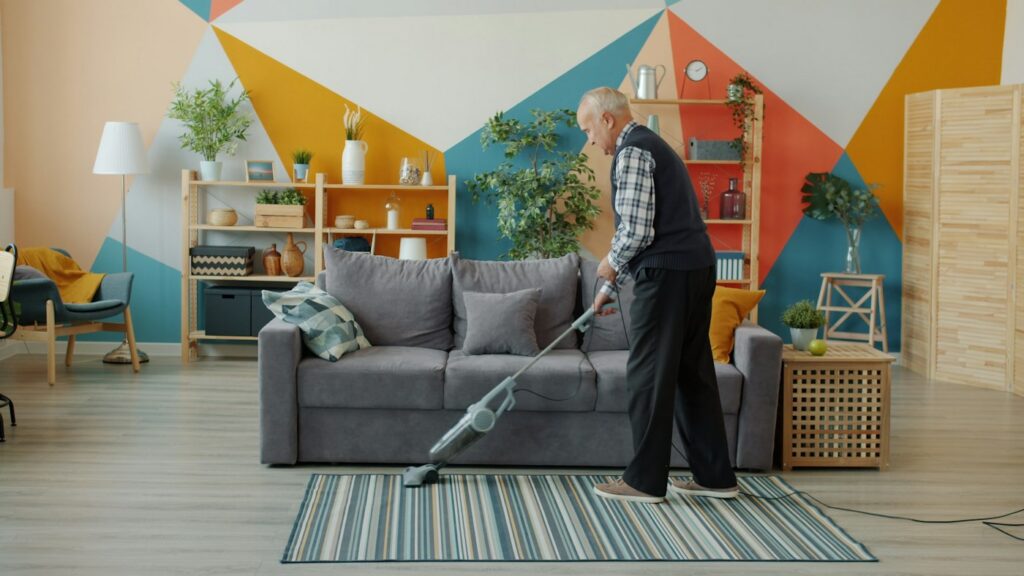 Retired homeowner vacuuming a rug between professional visits in a lower-traffic home suited to monthly cleaning